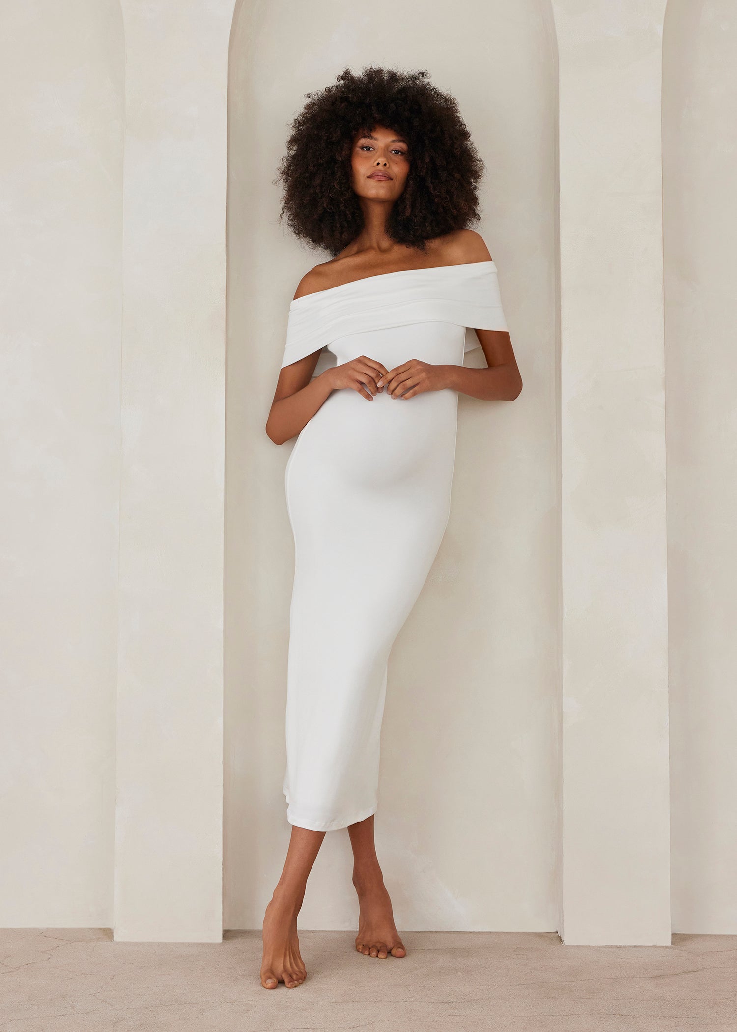 Woman wearing a white off-shoulder dress against a plain background